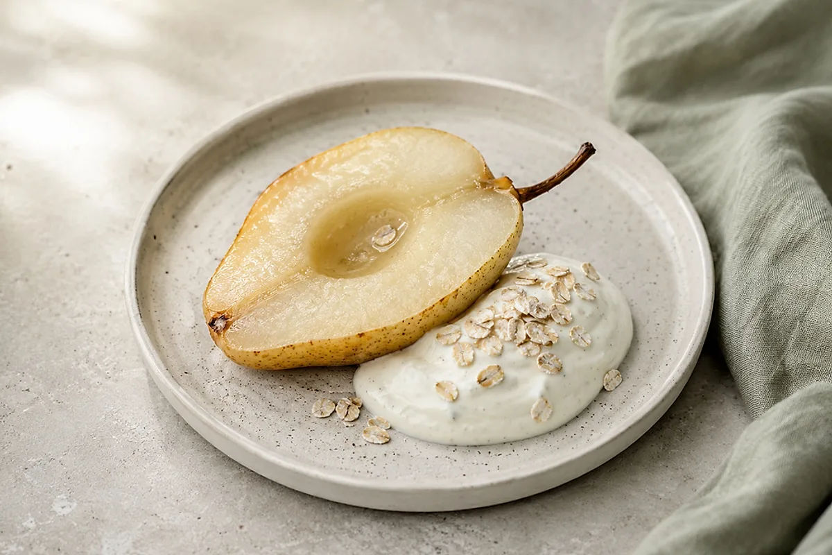 Warme, gebackene Birnenhälften mit einem Klecks Vanillequark in einer hellen Schale.