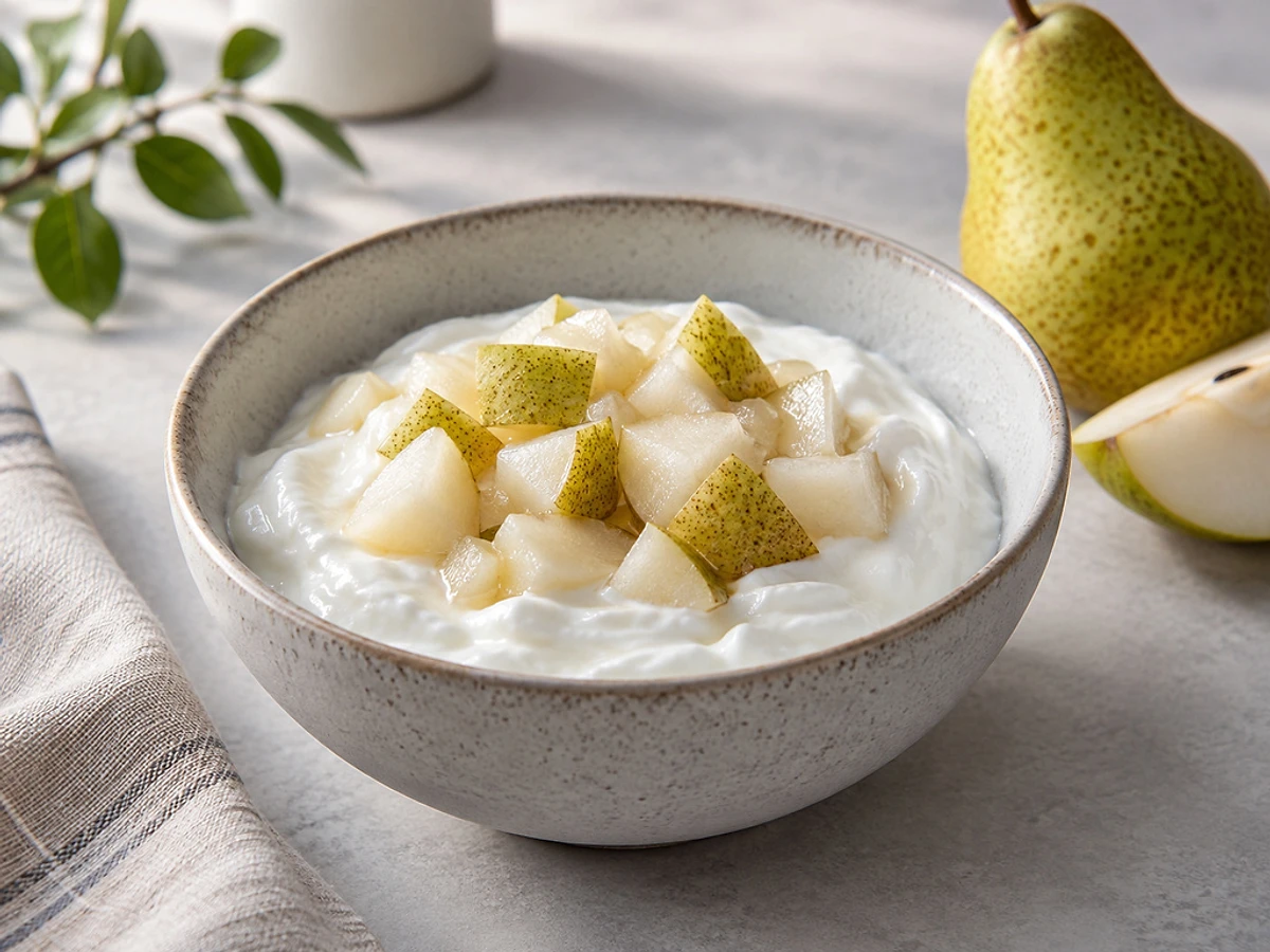 Schale mit cremigem Skyr, warmen Birnenwürfeln und einer Prise Zimt